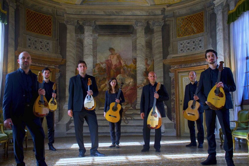A group of musicians with string instruments in a grand hall with classical architecture. 1