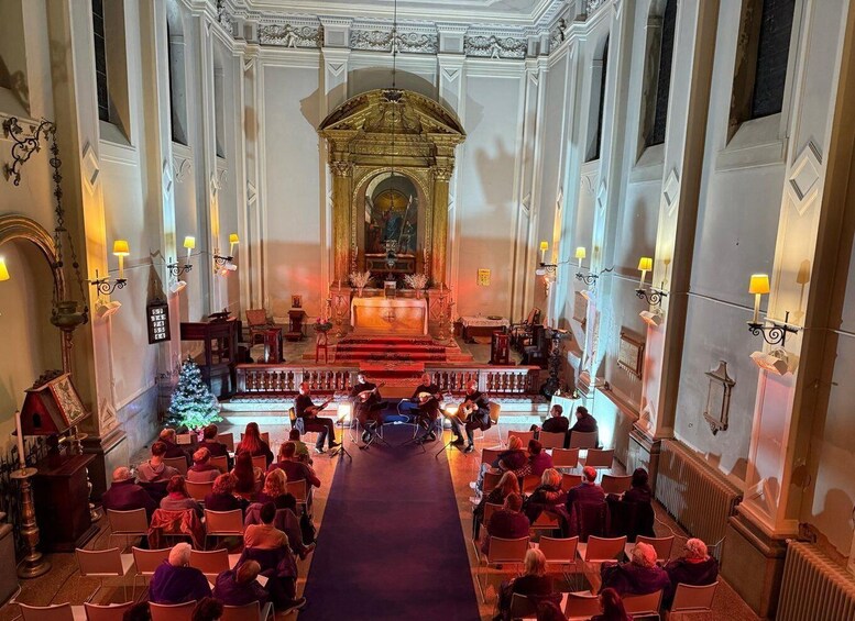 An ornate church interior with pews, a central altar, and a Christmas tree. 5