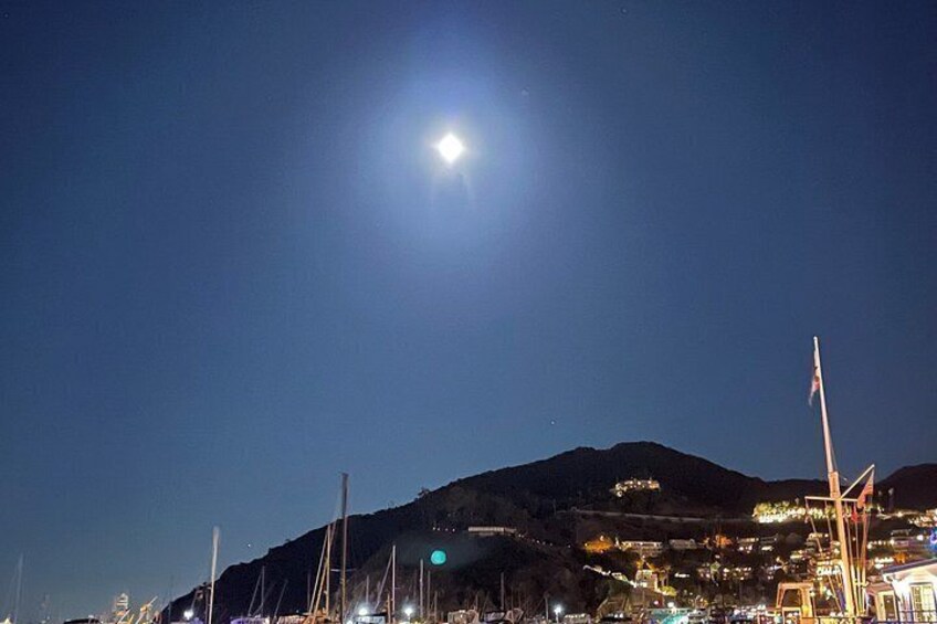 Une scène nocturne avec une lune brillante, une montagne et un paysage urbain illuminé. 2