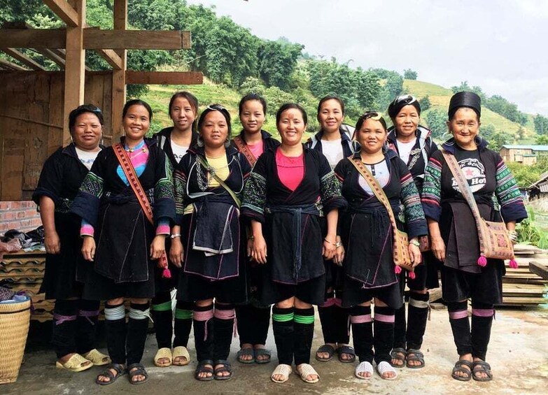 A group of people standing outdoors, wearing traditional clothing with colorful patterns and accessories. 3