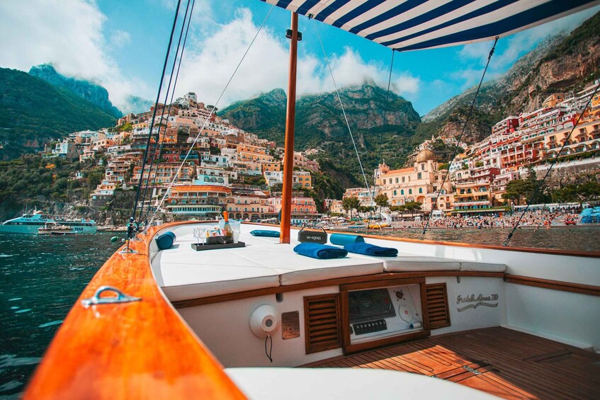 A boat with a wooden deck, a striped awning, and a view of colorful buildings on a hillside. 2