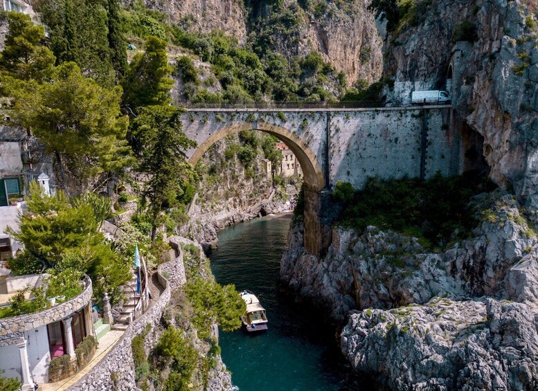 A stone bridge over a river, surrounded by rocky cliffs and greenery. 3