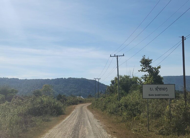 A rural road with a sign for Ban Samthong. 5