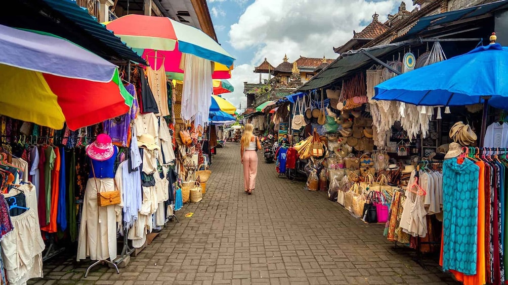 A bustling market street lined with colorful umbrellas and stalls selling clothes and accessories. 5