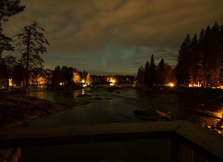 A river at night with a wooden dock, surrounded by trees and illuminated by distant lights. 2
