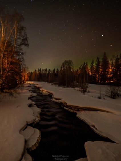 A snowy riverbank at night with the aurora borealis in the background. 3