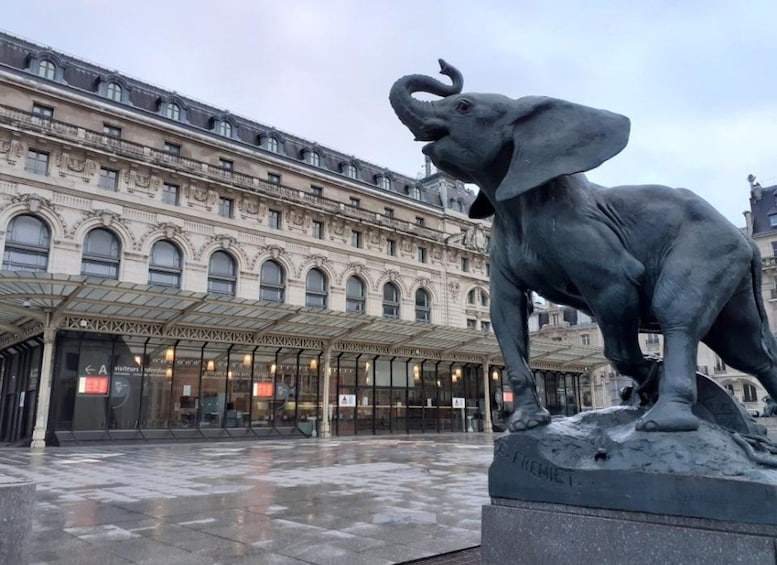 A bronze elephant statue in a square with a historic building in the background. 5