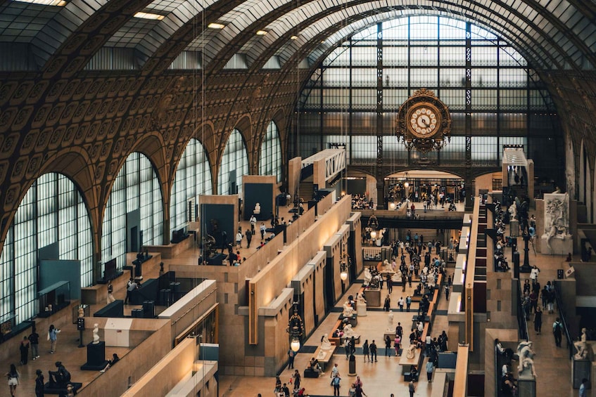 A large, ornate train station with high ceilings, arched windows, and a prominent clock. 3