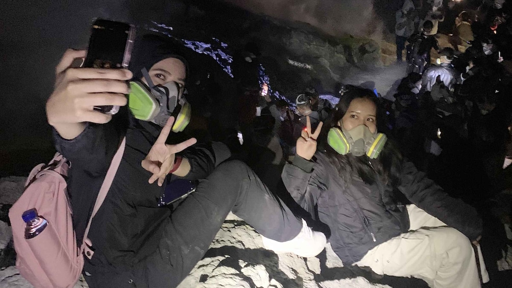 Two people taking a selfie in a crowded, dark outdoor setting. 5