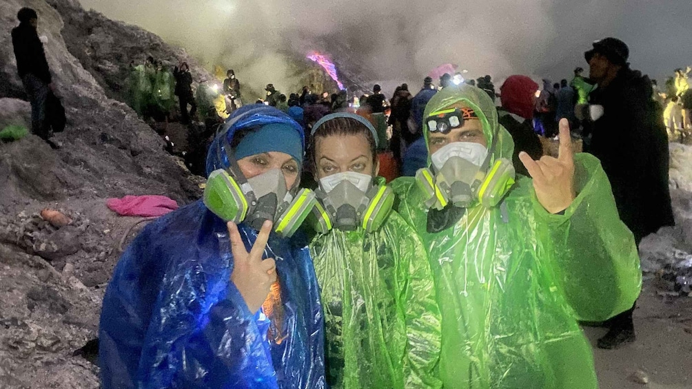 People in rain gear and gas masks at a nighttime outdoor event. 3