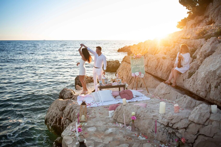 A couple dancing on a rocky seaside with a sunset in the background. 5