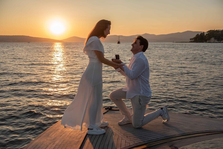 A couple on a boat at sunset with a cityscape in the background. 1