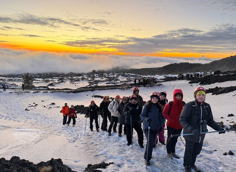 A group of people hiking in a snowy landscape during sunset. 1