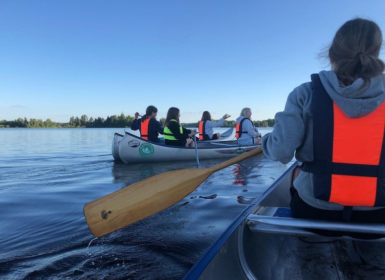 A group of people in a canoe on a calm lake, wearing life jackets. 1