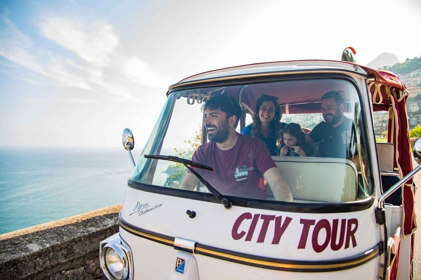 A CITY TOUR vehicle with passengers, overlooking a coastal landscape. 1