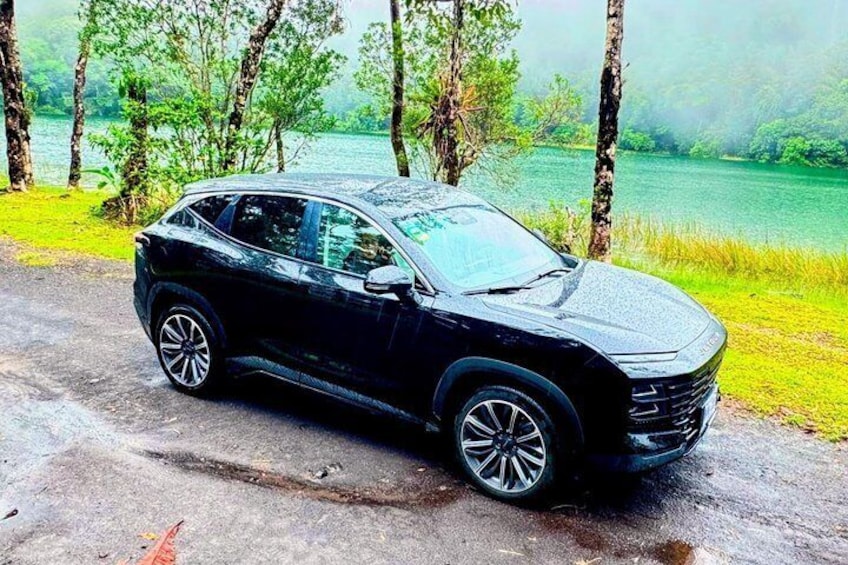 En svart SUV står parkerad vid en väg, med en sjö och träd i bakgrunden. 3