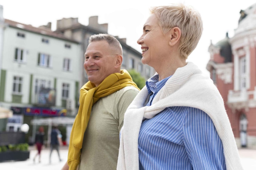 Two people standing on a street with buildings in the background. 4