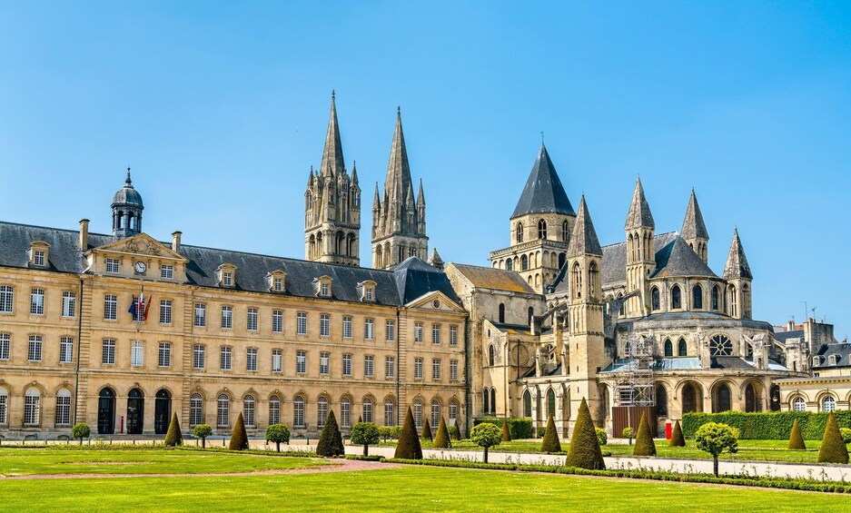 A historic building with multiple spires and a well-manicured garden. 1