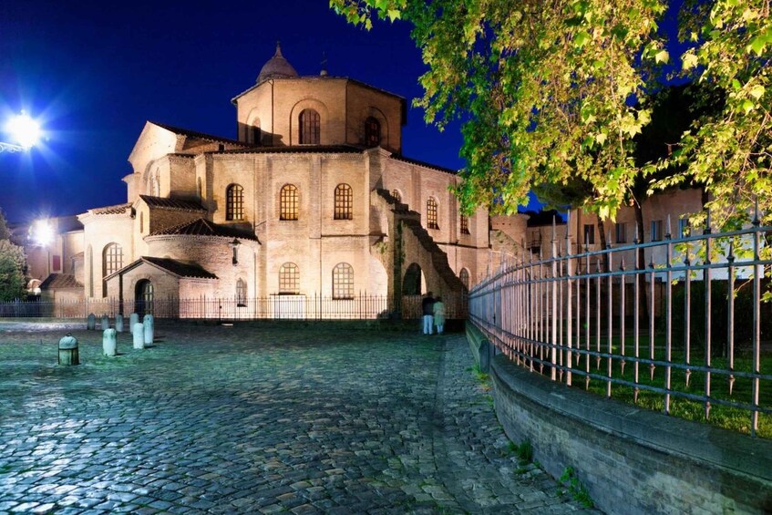 A historic church with a dome and arched windows, surrounded by a cobblestone courtyard and a metal fence. 2