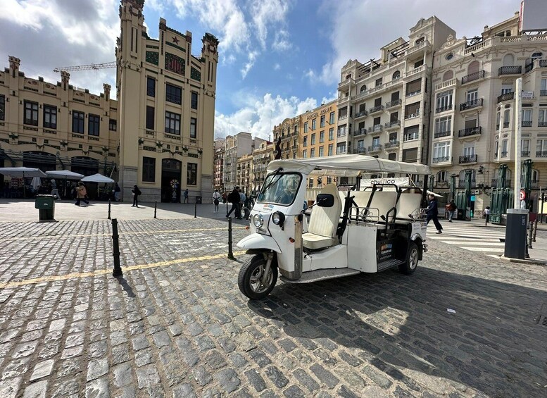 A tuk-tuk parked on a cobblestone street with historic buildings in the background. 2
