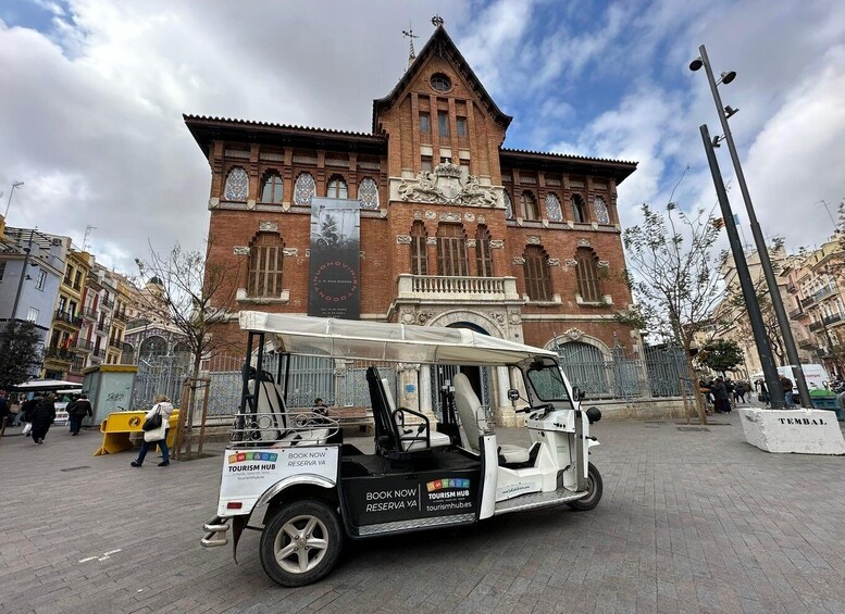 A white tour vehicle parked in front of a historic building with a large banner. 5
