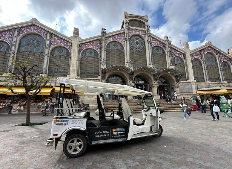A white tuk-tuk parked in front of a historic building with ornate architecture. 4