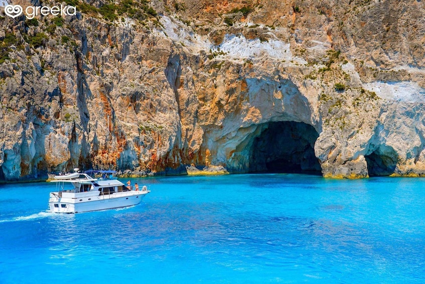 A boat on a clear blue sea with rocky cliffs and a cave entrance. 2