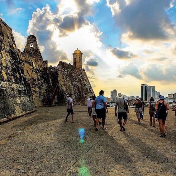 A group of people walking along a historical site with ancient walls and a tower. 2