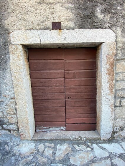 A stone wall with a wooden door and a metal plate above it. 2