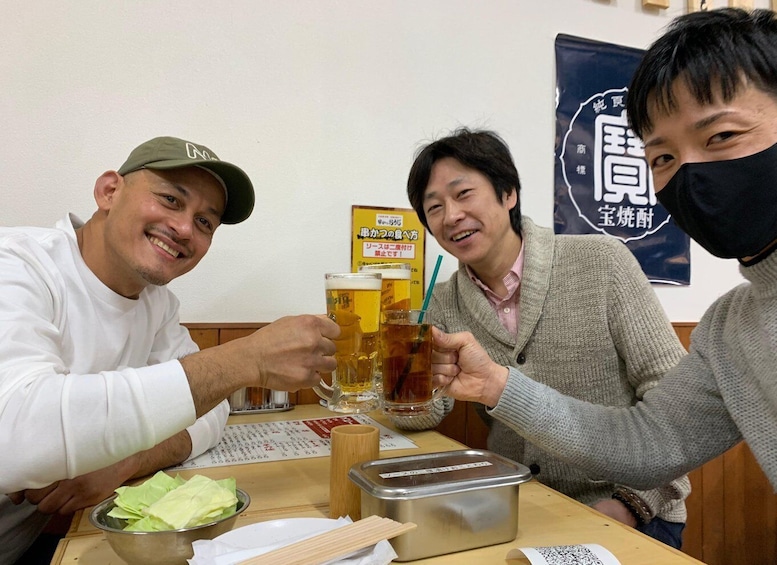 Three people toasting with beer glasses at a restaurant. 4
