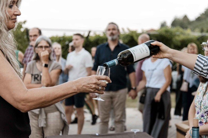 A person pouring wine into a glass at an outdoor event. 4