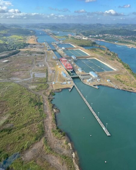 An aerial view of a coastal industrial area with a large waterway, a dock, and several buildings. 5