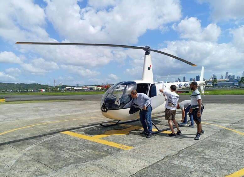 A helicopter on a tarmac with people boarding it. 4