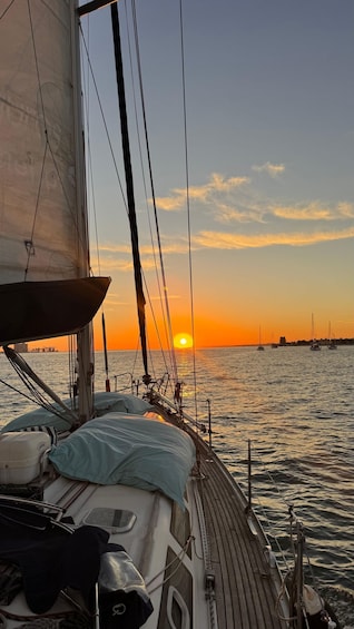 A sailboat at sunset with the sun setting on the horizon. 1