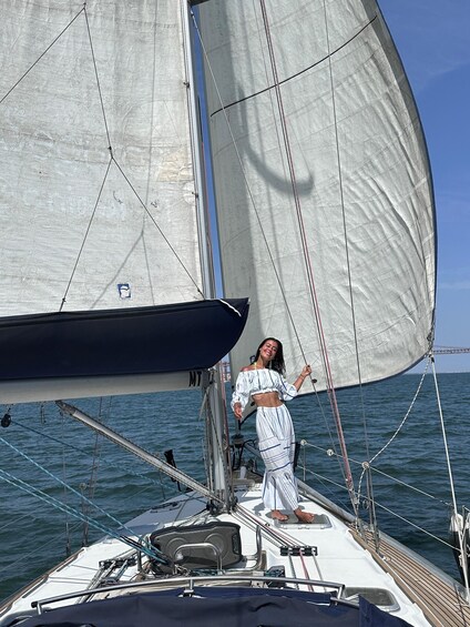 A person on a sailboat with sails unfurled, standing on the deck. 5