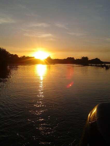 A sunset over a calm body of water with a boat in the foreground. 5