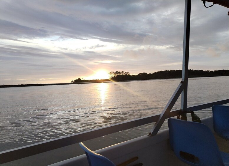 A sunset over a calm body of water with a boat in the foreground. 3