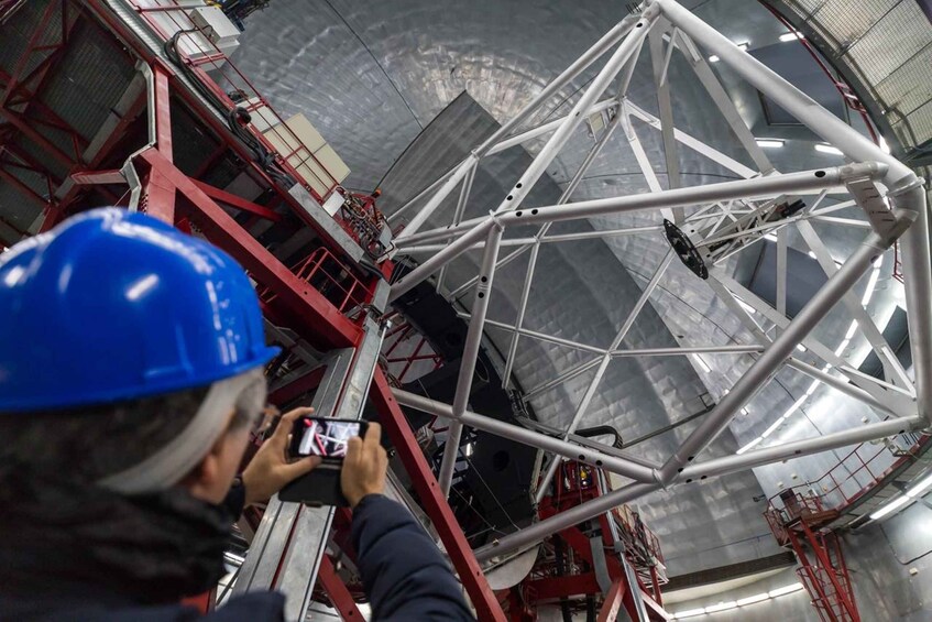 A person taking a photo of a large, complex metal structure inside a building. 5