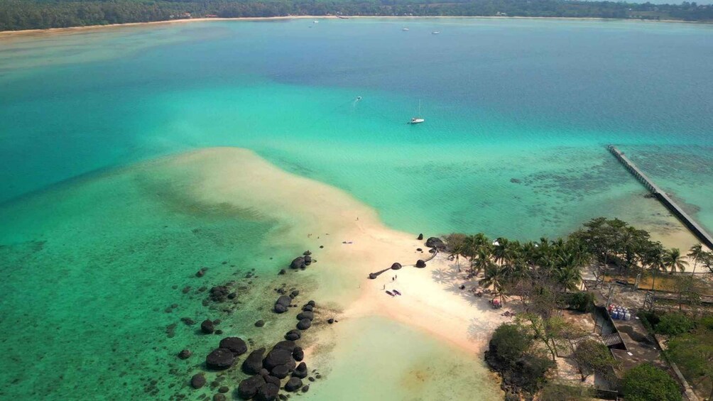 A coastal landscape with clear turquoise waters, a sandy beach, and a pier extending into the sea. 5
