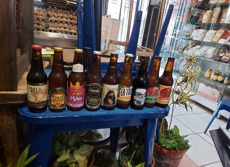 A selection of beer bottles on a blue shelf in a store. 1