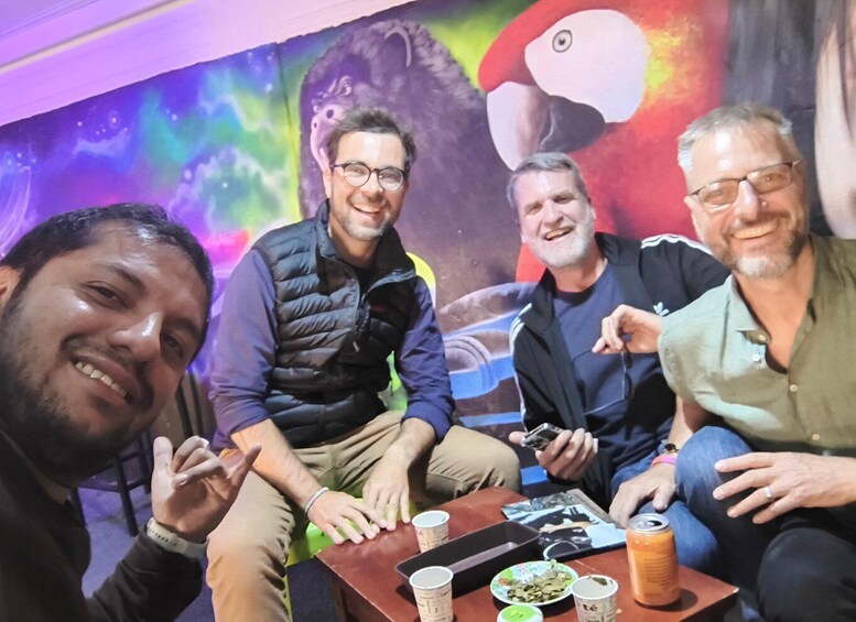 Four people seated at a table with a colorful mural in the background. 4