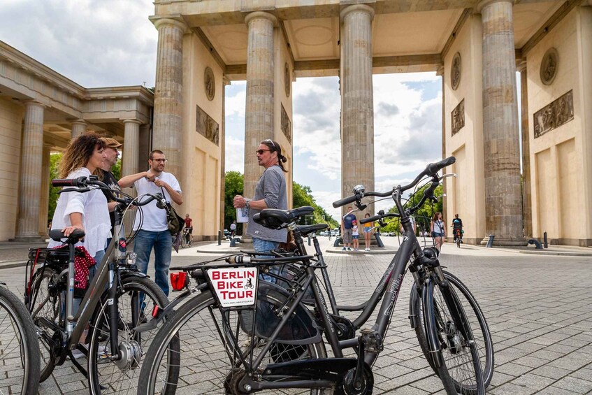 A group of people with bicycles in front of a classical building with columns. 3