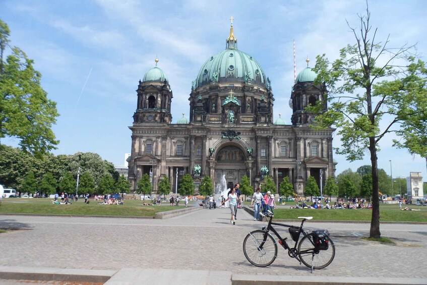 A large historic building with domes and a fountain in the foreground. 2