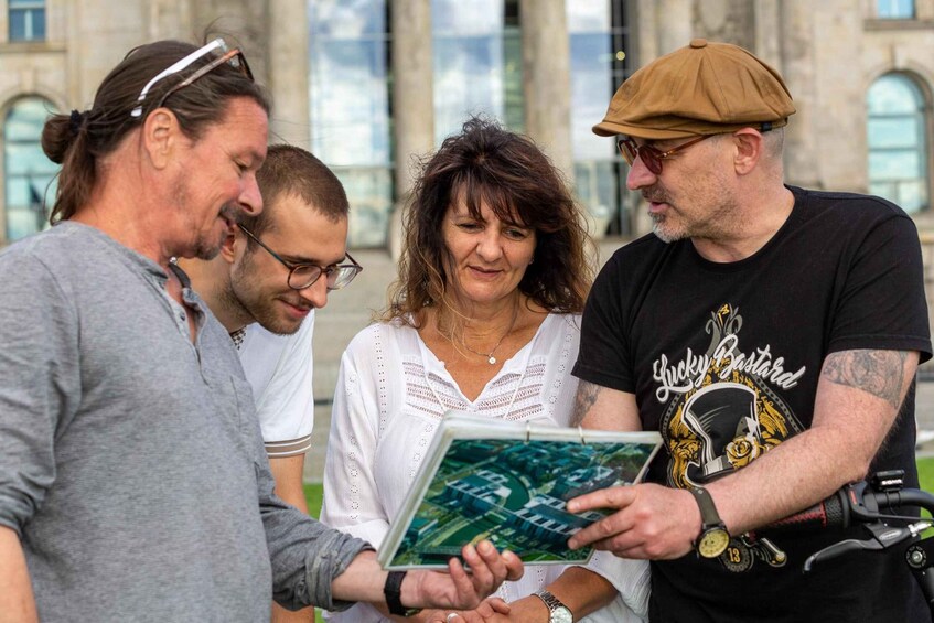 A group of people examining a map outdoors with a historic building in the background. 1
