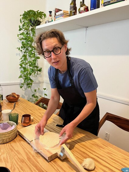 A person rolling dough on a wooden board in a kitchen. 2