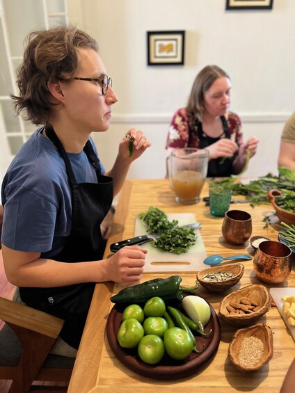 Two people preparing food at a wooden table with vegetables, a cutting board, and bowls. 4