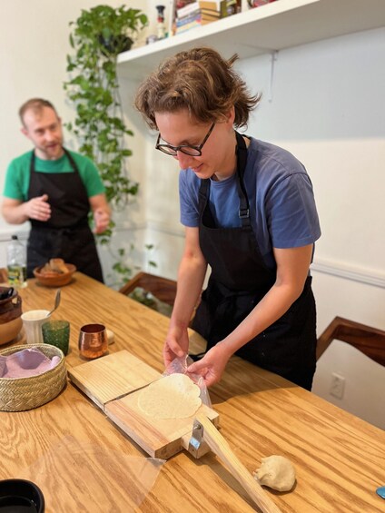 A person rolling dough on a wooden board in a kitchen. 3