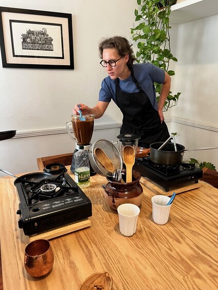 A person preparing a drink with a blender and a stove. 1