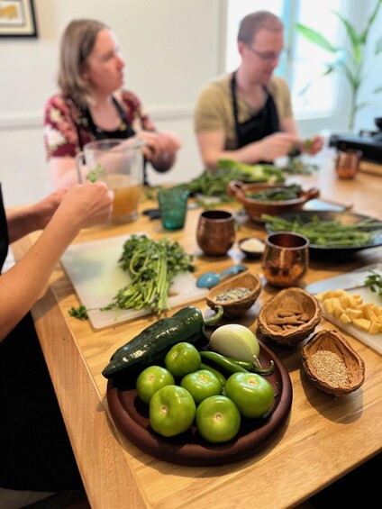 A kitchen counter with fresh vegetables and a bowl of green apples. 5
