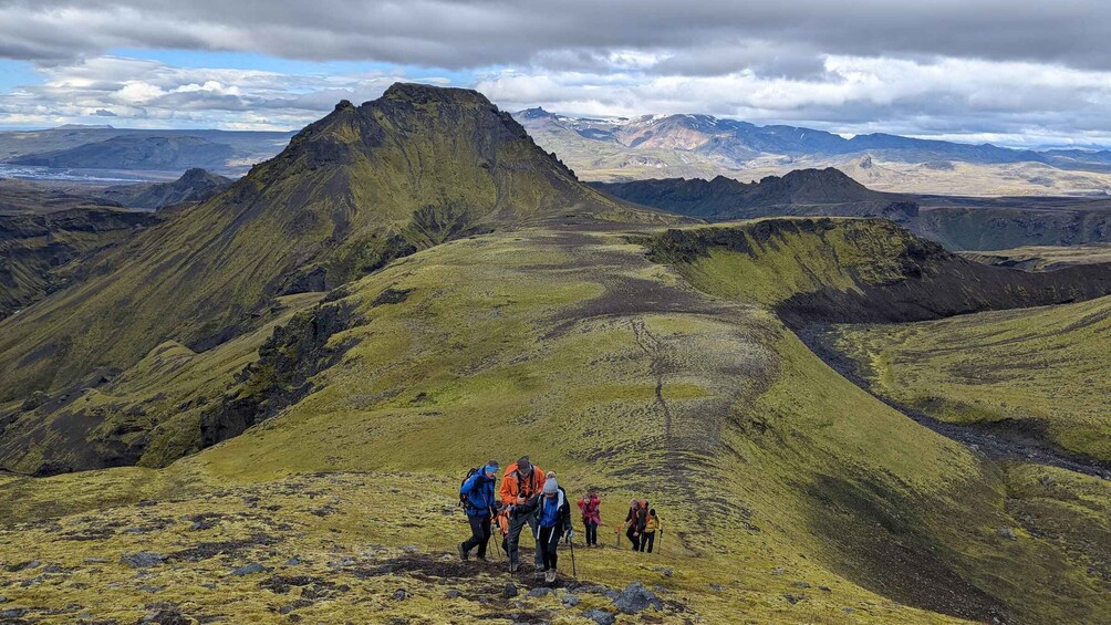 A group of hikers on a mountain trail with a prominent peak in the background. 1